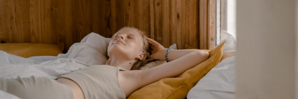 A woman enjoys a tranquil moment lying on her back in a cozy wooden bedroom.